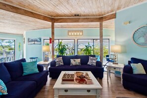 A spacious living area with two dark blue sofas, a white coffee table, and a large window offering a view of greenery. - Ozello Waterfront Paradise (Crystal River)