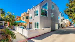 A modern two-story house with large windows, a garage, and a white fence. - Steps to Bay & Beach | Rooftop Deck, Fire Pit, AC, Garage, Views (San Diego)