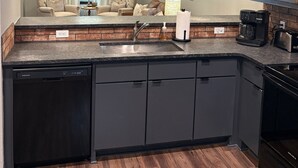 Ett modernt kök med en inbyggd diskmaskin, en kaffebryggare och en brödrost. Det finns två hänglampor och en takfläkt.