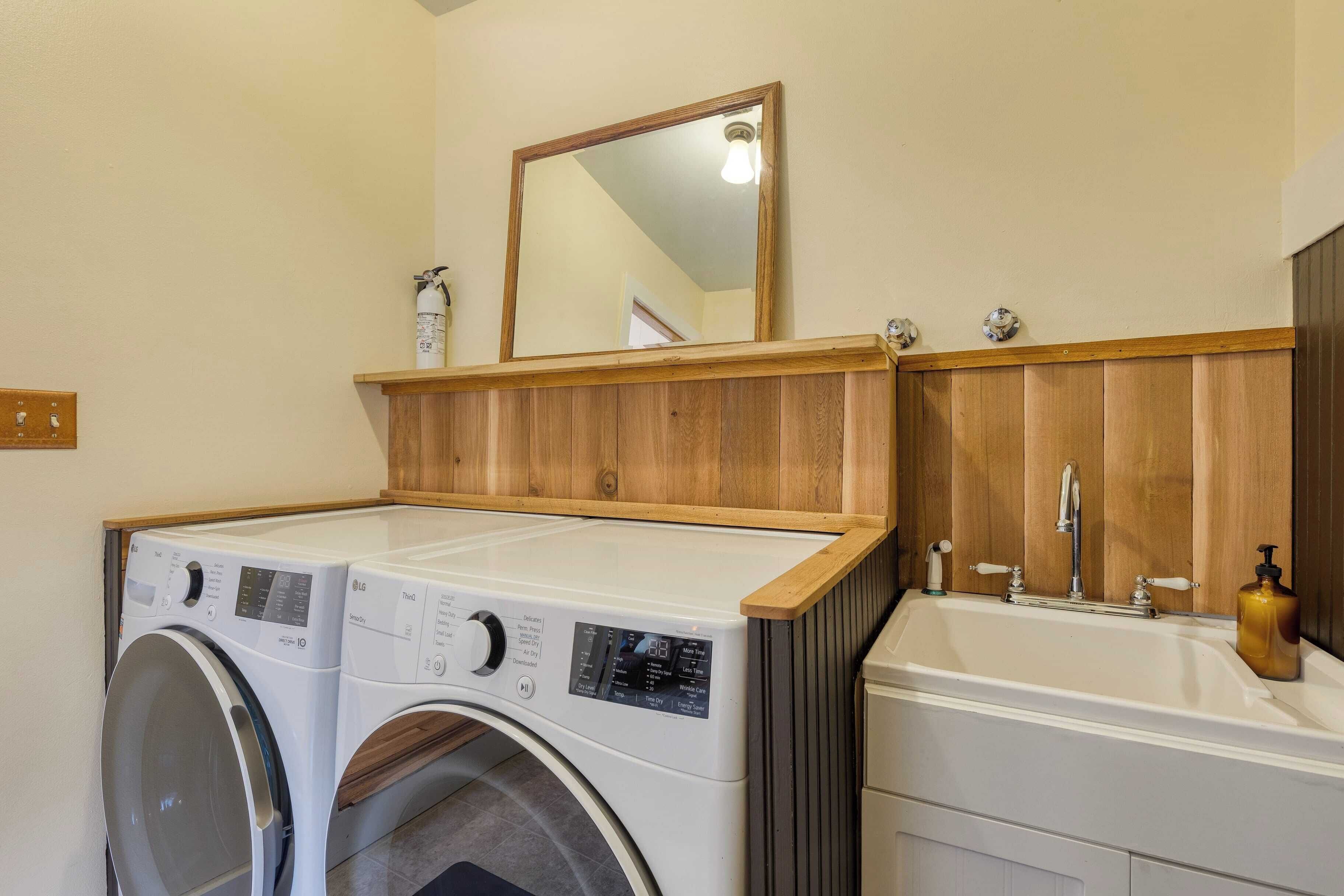 A laundry area with two washing machines, a sink, and a mirror.
