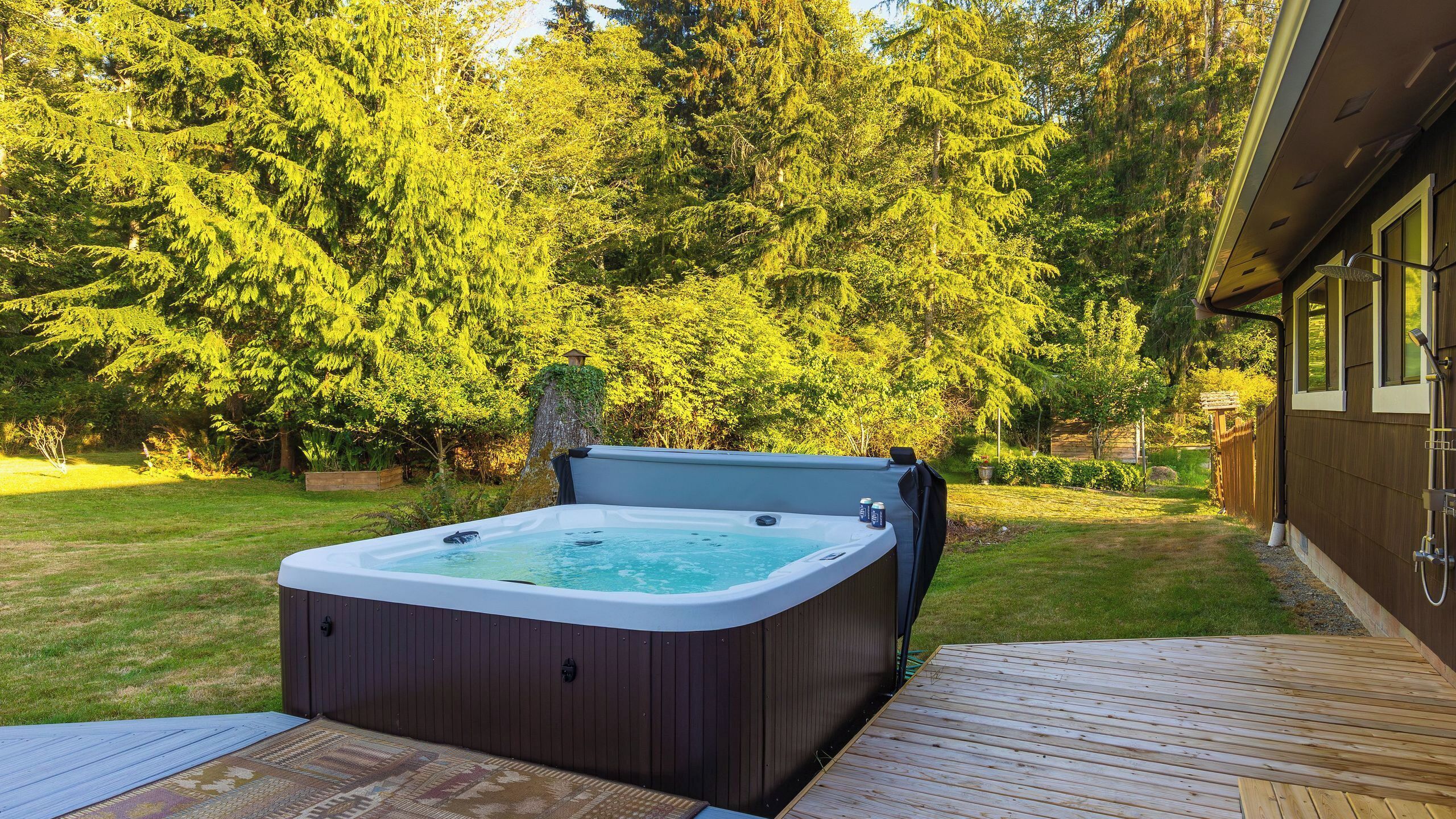 Un bain à remous sur une terrasse en bois, avec une maison en arrière-plan.
