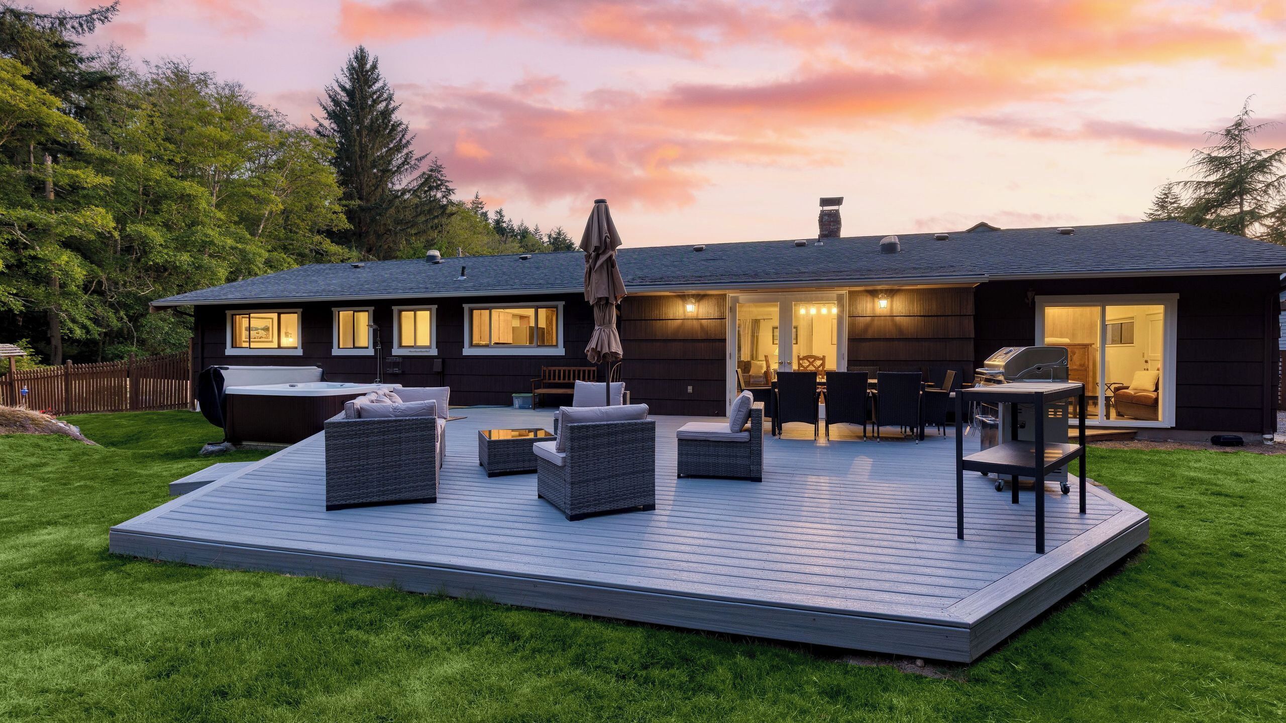 A modern house with a deck, outdoor seating, and a hot tub.