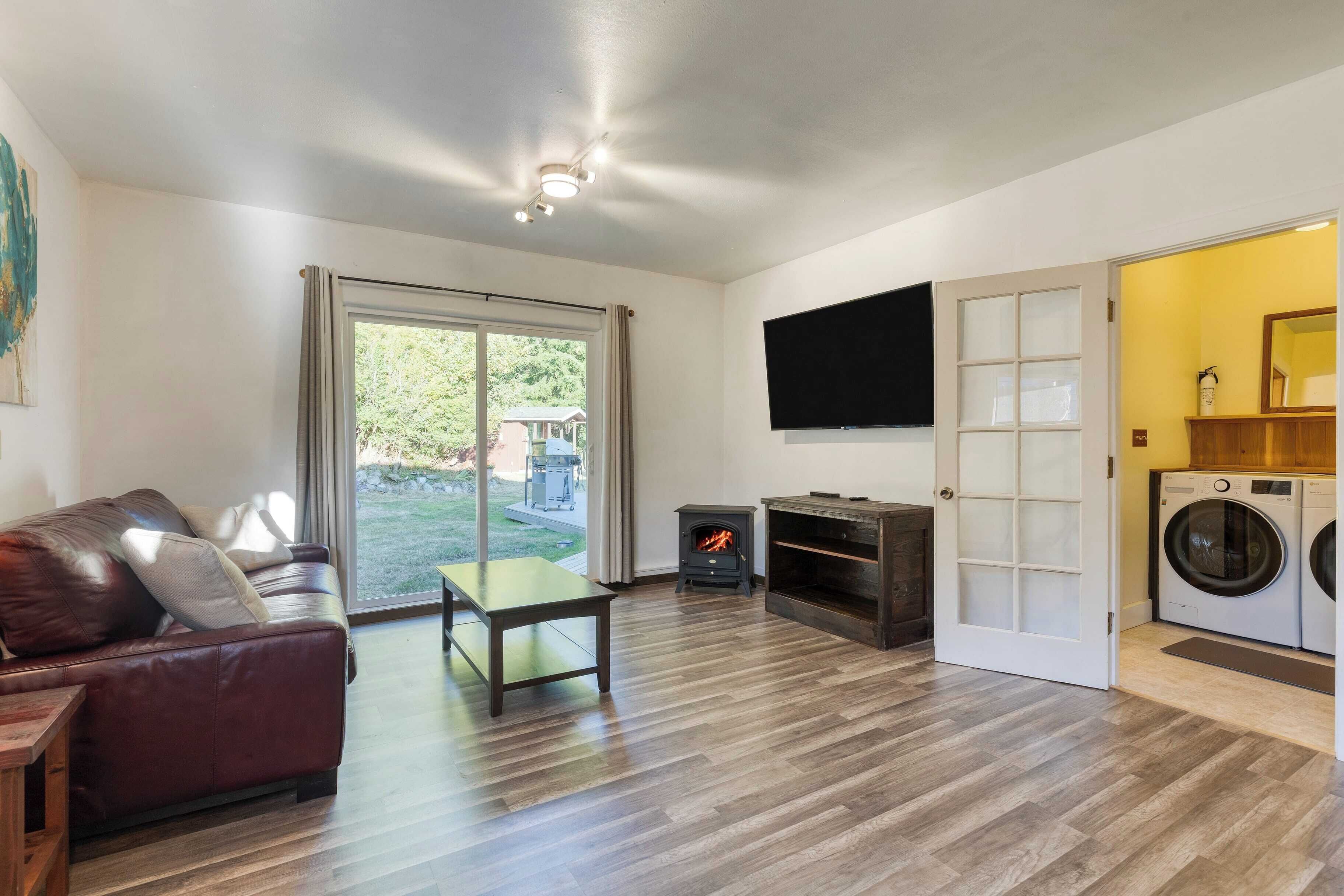 A spacious living room with a sofa, a table, a fireplace, a TV, and a washing machine.