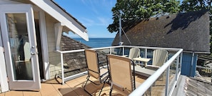 A balcony with a view of the sea, a chair, and a table.