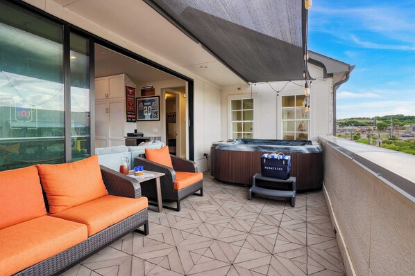 Un balcon avec un canapé, une table, un jacuzzi et une vue sur la ville.