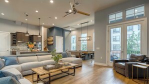 A spacious living area with a large sofa, a coffee table, and a dining area with a table and chairs. - Town Lake Townhouse by Avantstay Hot Tub, Game Room & Skyline Views (Austin)