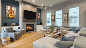Un salon moderne doté d’une cheminée, d’un téléviseur à écran plat et d’une grande fenêtre.