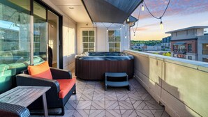 A balcony with a hot tub, wicker furniture, and a view of the city. - Town Lake Townhouse by Avantstay Hot Tub, Game Room & Skyline Views (Austin)