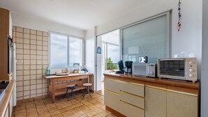A compact kitchen with a wooden countertop, a built-in oven, a microwave, and a vintage radio. - Charmante villa vue mer (Grasse Magagnosc)