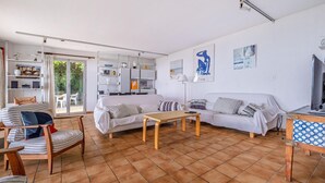 A spacious living room with a sofa, a wooden coffee table, and a TV. There is a sliding glass door leading to a balcony. - Charmante villa vue mer (Grasse Magagnosc)