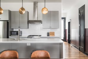 A modern kitchen with a central island, stainless steel appliances, and pendant lighting. - Sleeps 36, 3 Homes Walk to Germantown Modern Townhomes Near DT Avantstay (Nashville)