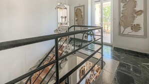 Eine Treppe mit Metallgeländer, einer Glasböden und Kunstwerken an den Wänden.