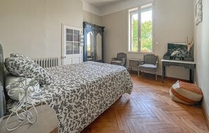 A bedroom with a bed, a desk, a chair, and a radiator.