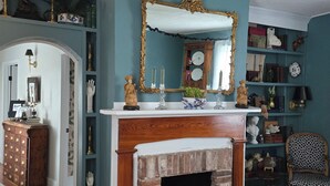Une pièce avec une cheminée, des étagères à livres et un miroir.
