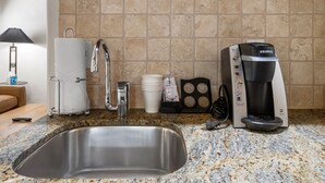 Een keuken met een roestvrijstalen spoelbak, een koffiezetapparaat en een papieren handdoekdispenser.