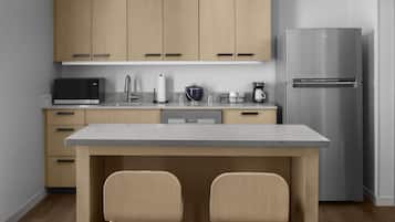 A modern kitchen with wooden cabinets, a stainless steel refrigerator, a microwave, and a coffee maker.