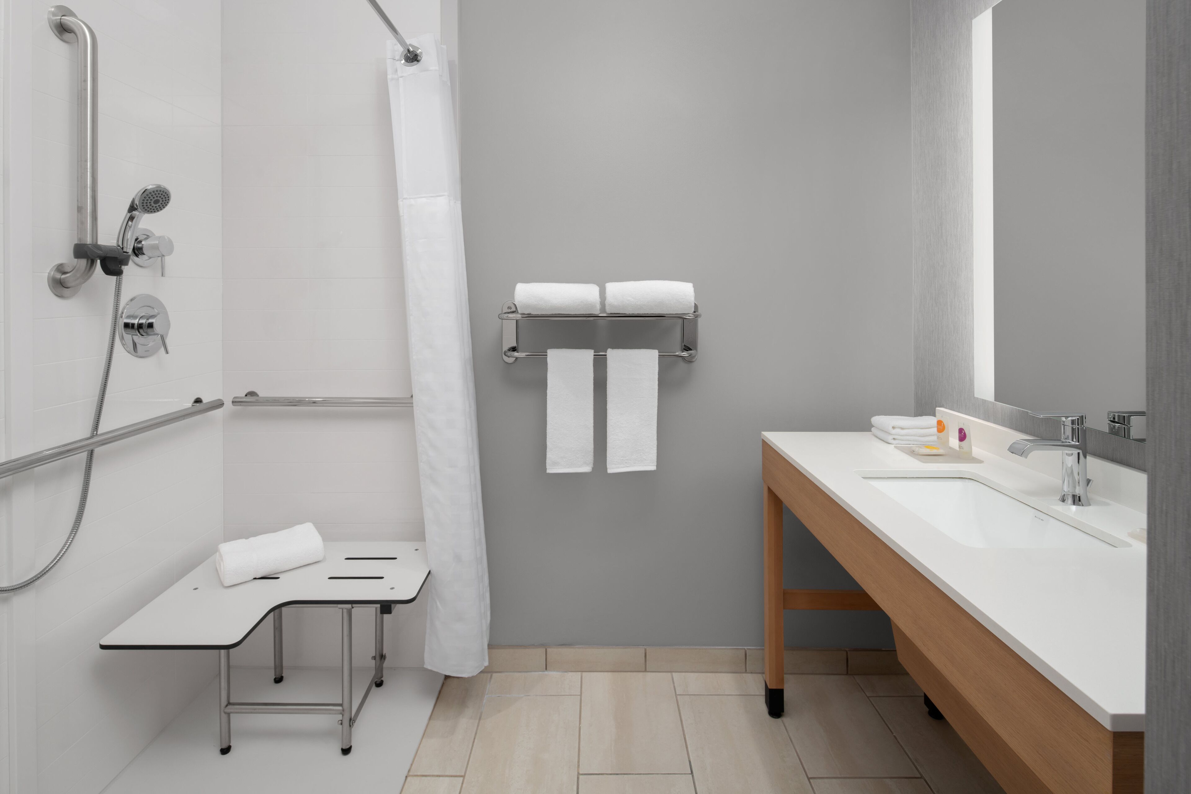 Un baño moderno con ducha, lavabo y toallero.