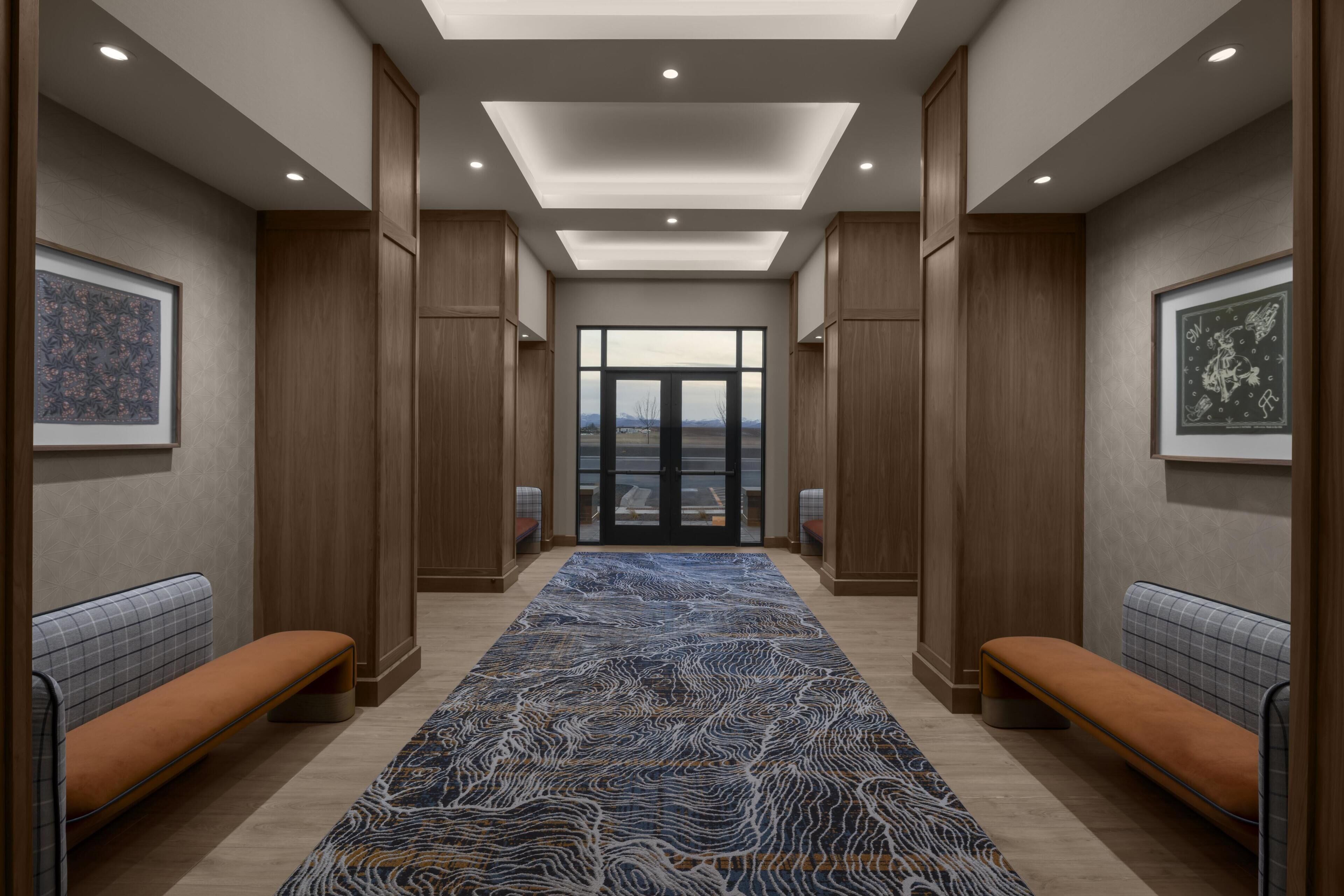 Un couloir avec des bancs, des œuvres d’art encadrées et un tapis à motifs.