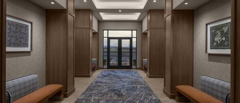 Un couloir avec des bancs, des œuvres d’art encadrées et un tapis à motifs.