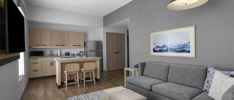 A modern living space with a kitchen, dining area, and a gray sofa with an ottoman.
