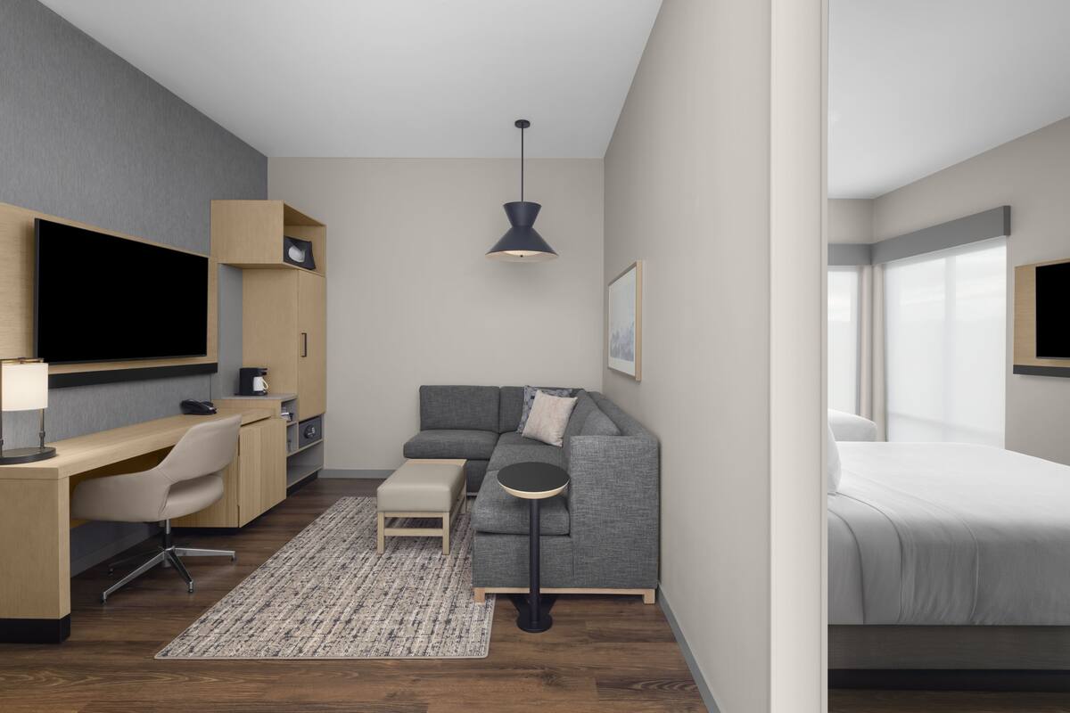 Habitación de hotel moderna con sofá, escritorio y cama.