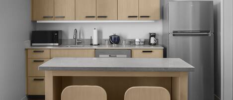 Una cocina moderna con armarios de madera, un refrigerador de acero inoxidable, un microondas y una cafetera.