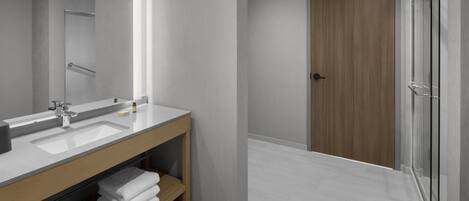 A modern bathroom with a large mirror, two sinks, a wooden vanity, and a glass shower enclosure.