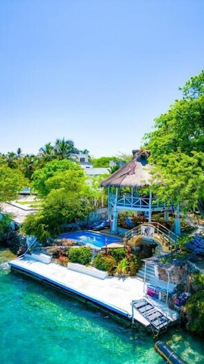 A tropical resort with a thatched-roof gazebo, a swimming pool, and lush greenery. - HOTEL ISLA MULATA (Rosario Islands)