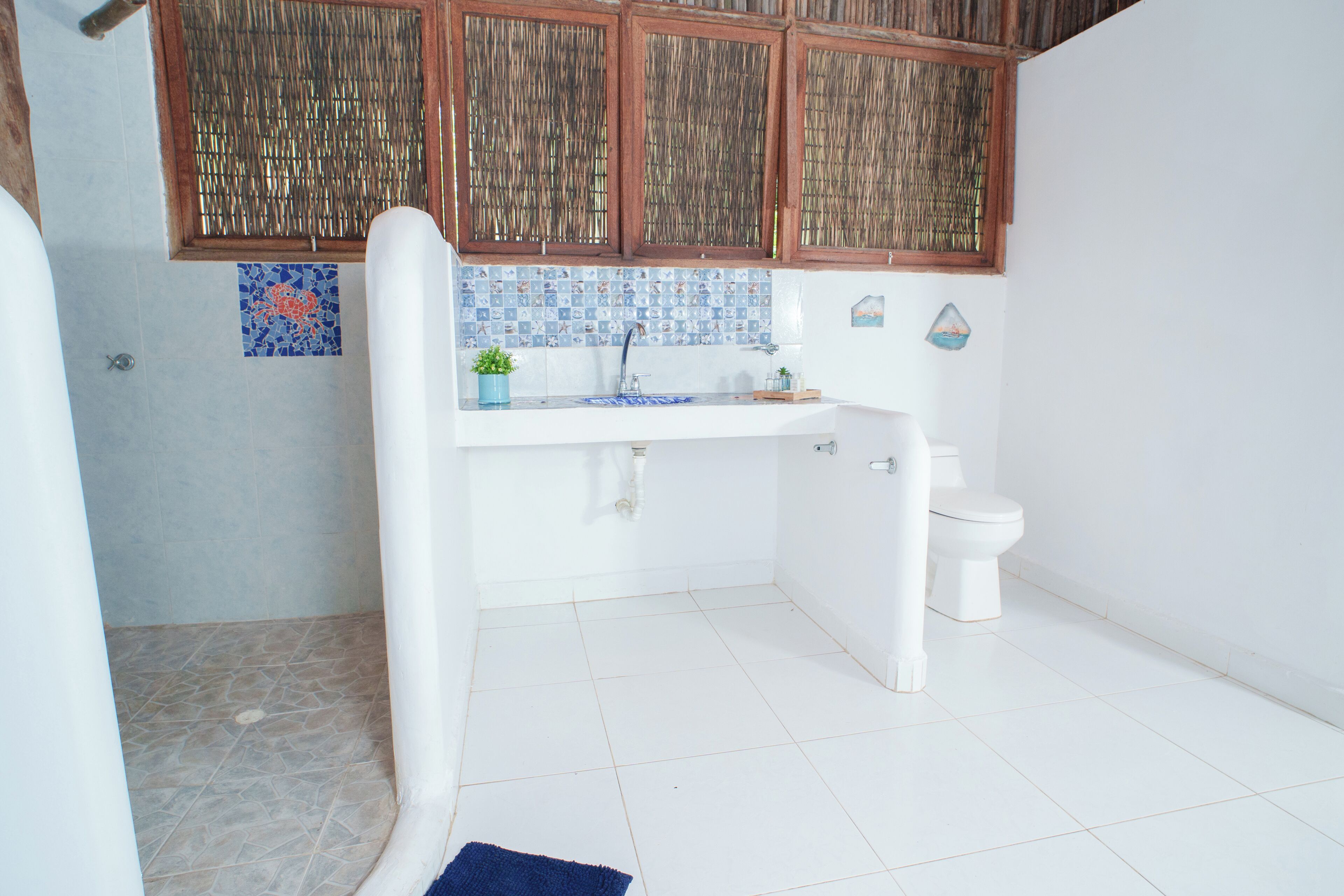 A bathroom with a shower, toilet, sink, and a decorative mosaic backsplash.
