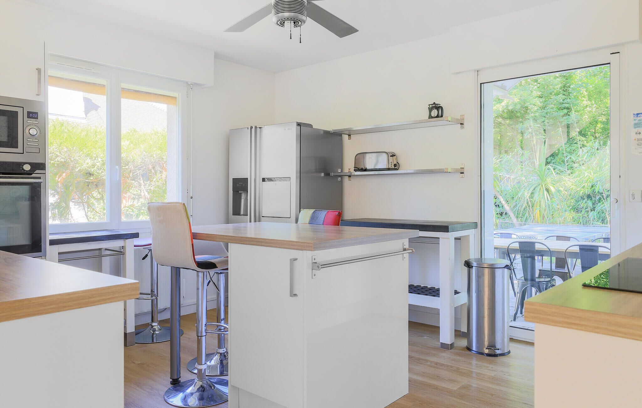 A modern kitchen with a central island, a microwave, a refrigerator, and a toaster.