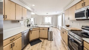 Una cocina moderna con armarios de madera, electrodomésticos de acero inoxidable y una isla central.