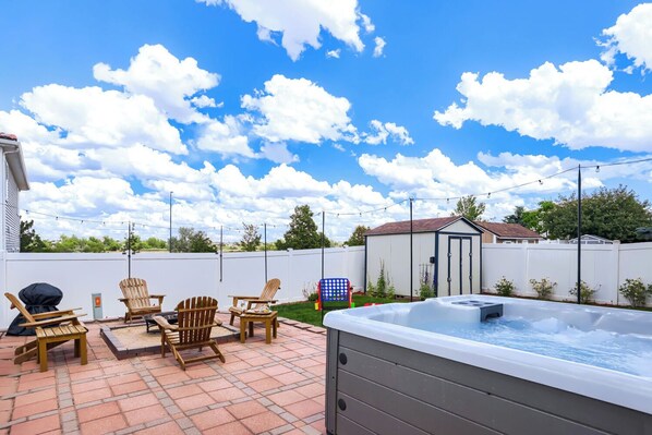 Un patio trasero con un jacuzzi, mobiliario de jardín y un cobertizo.