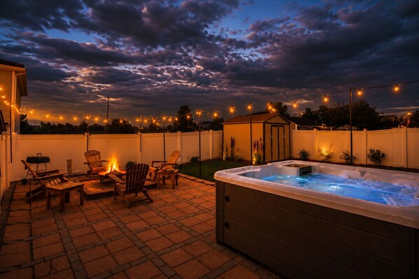 Une terrasse extérieure dotée d’un jacuzzi, d’un espace salon et de guirlandes lumineuses.