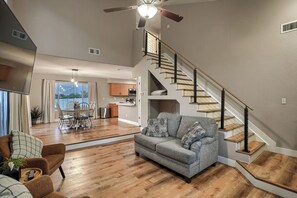 A spacious living area with a sofa, dining table, and staircase.