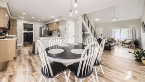 Una cocina moderna con armarios blancos y un comedor con mesa negra y sillas blancas.