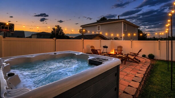 Patio con jacuzzi, muebles de exterior e iluminación colgante.