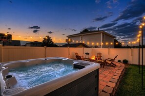 Patio con jacuzzi, muebles de exterior e iluminación colgante.