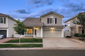 A two-story residential house with a garage, a small front porch, and a well-maintained lawn.