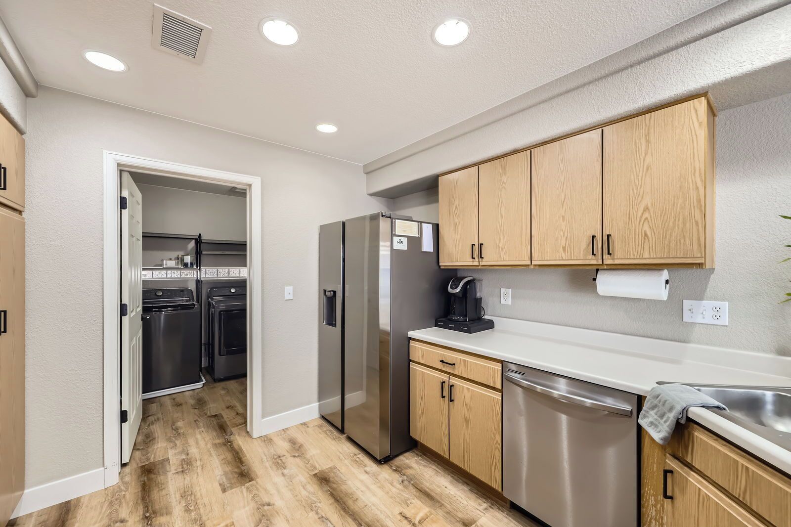 A modern kitchen with wooden cabinets, stainless steel appliances, and a white countertop.