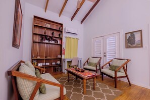 Un salon comprenant un canapé, deux fauteuils, une table basse, une bibliothèque et un tableau accroché au mur.