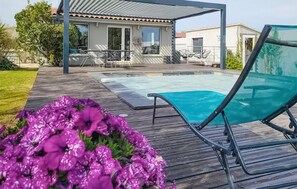 A wooden deck with a pool, outdoor furniture, and a house in the background. - Maison proche Alpilles (Arles)