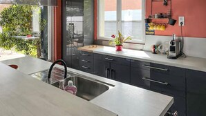 Una cocina moderna con un lavamanos de acero inoxidable, armarios negros y una ventana con vistas.