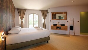 Een slaapkamer met een groot bed, een houten dressoir, een spiegel en een raam met gordijnen.