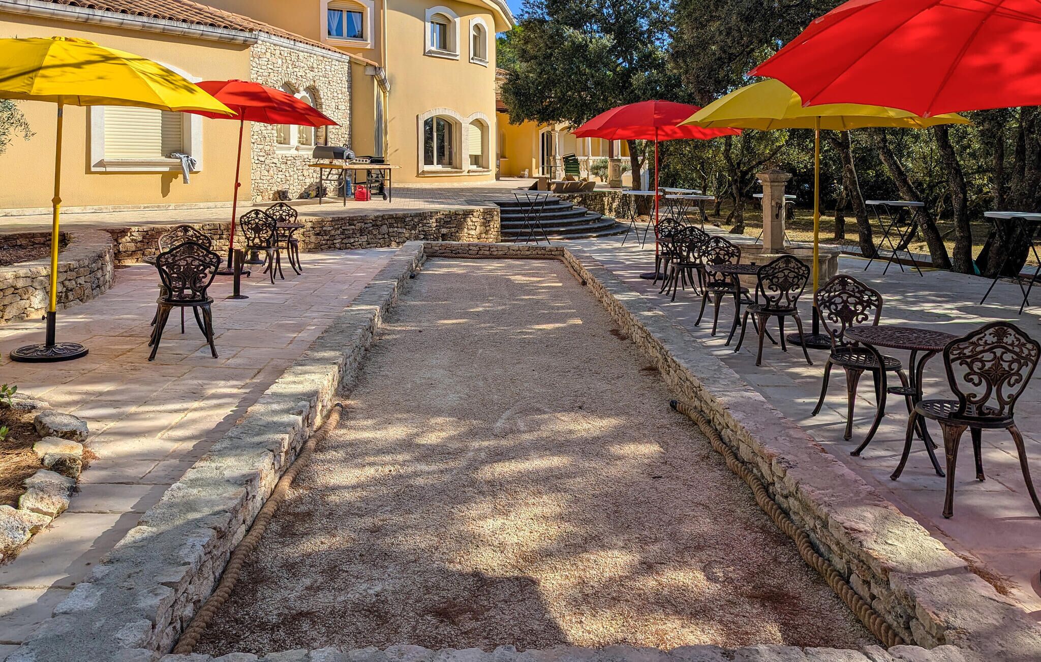 Un patio al aire libre con piso de piedra, mobiliario exterior y sombrillas.