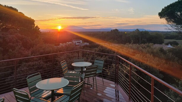 Een terras met buitenmeubels en uitzicht op de zonsondergang.