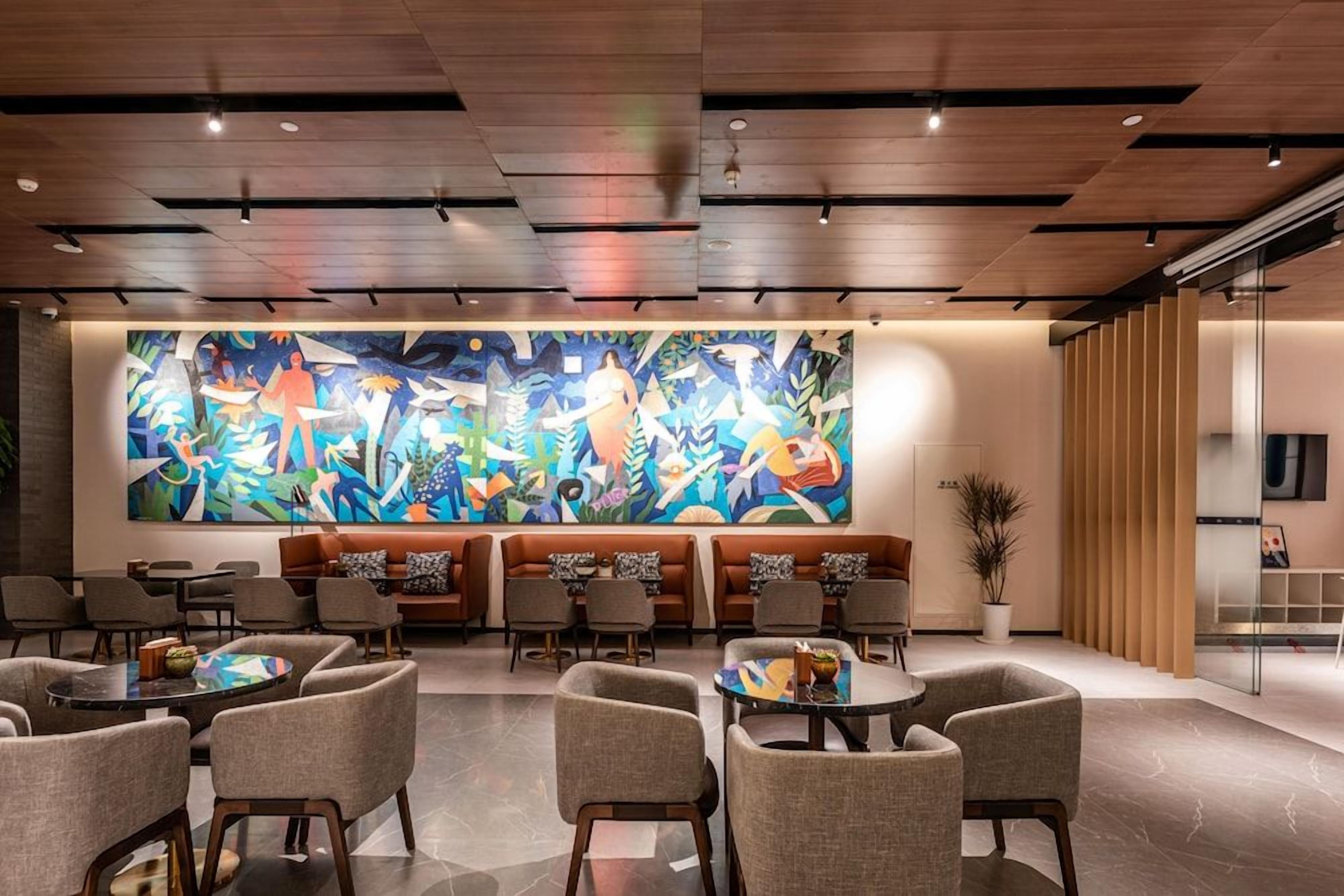 Un vestíbulo moderno con un gran mural abstracto, zonas de estar y un panel de vidrio.