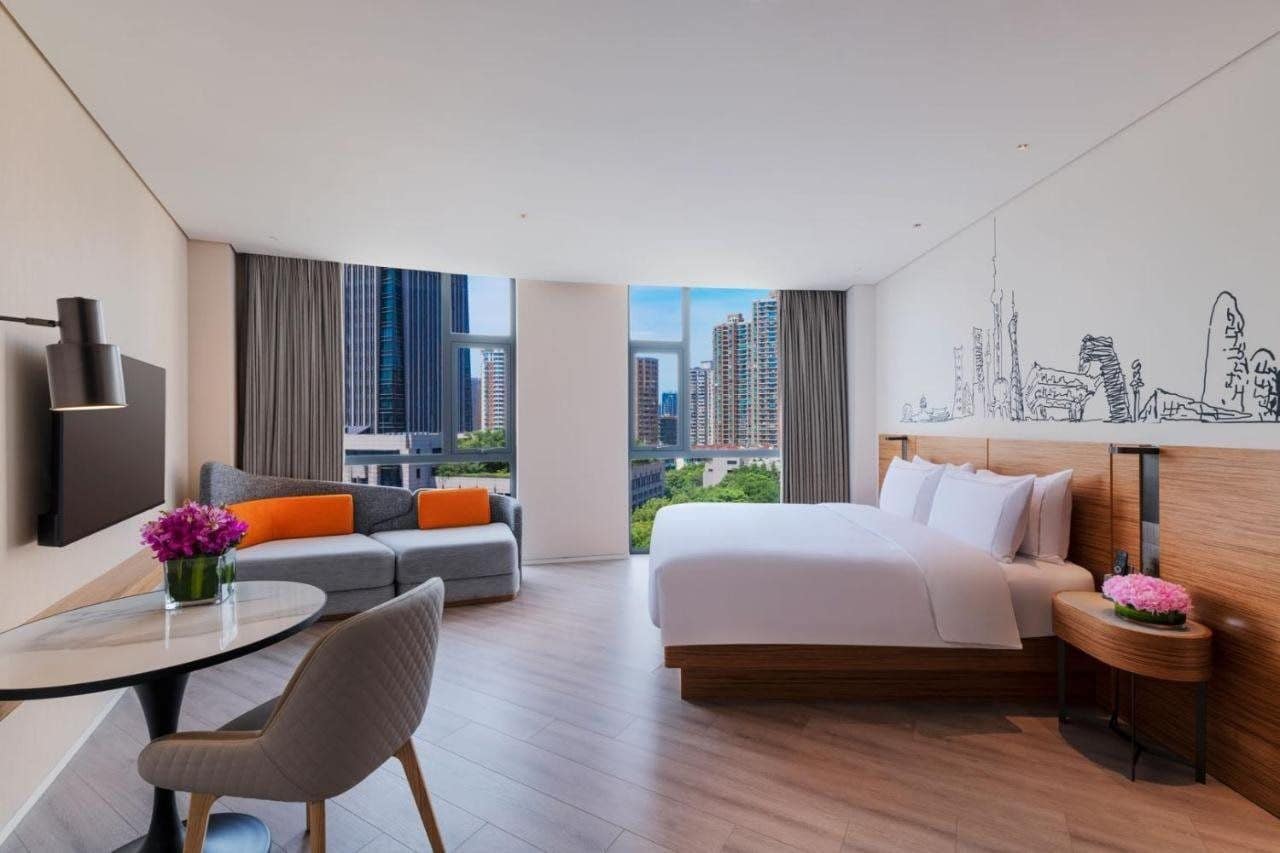 Una habitación de hotel moderna con cama, sofá y escritorio con silla.