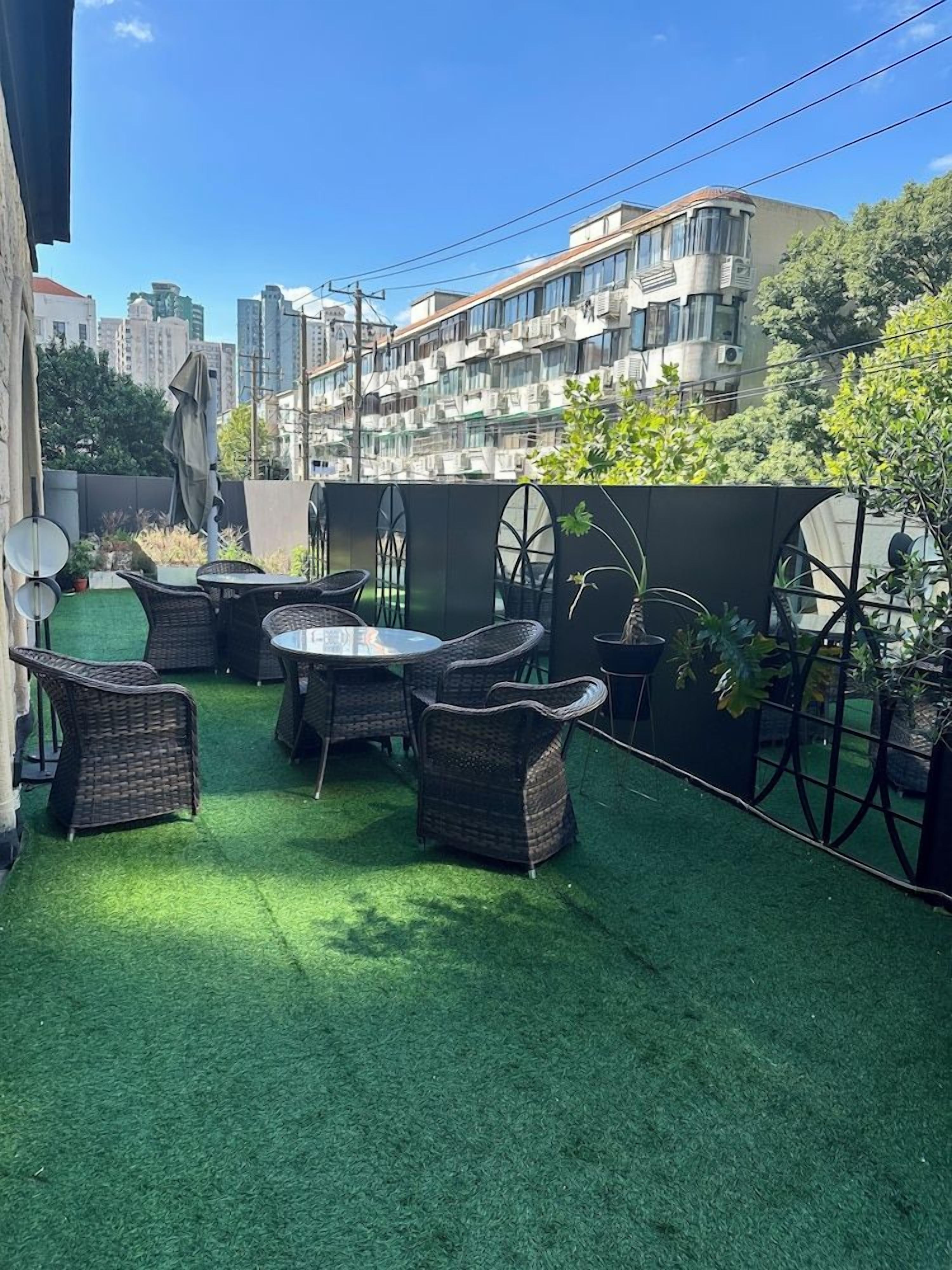 Un patio exterior con césped artificial, muebles de mimbre y plantas en macetas.