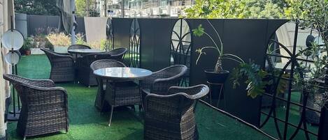 An outdoor patio with artificial grass, wicker furniture, and potted plants.