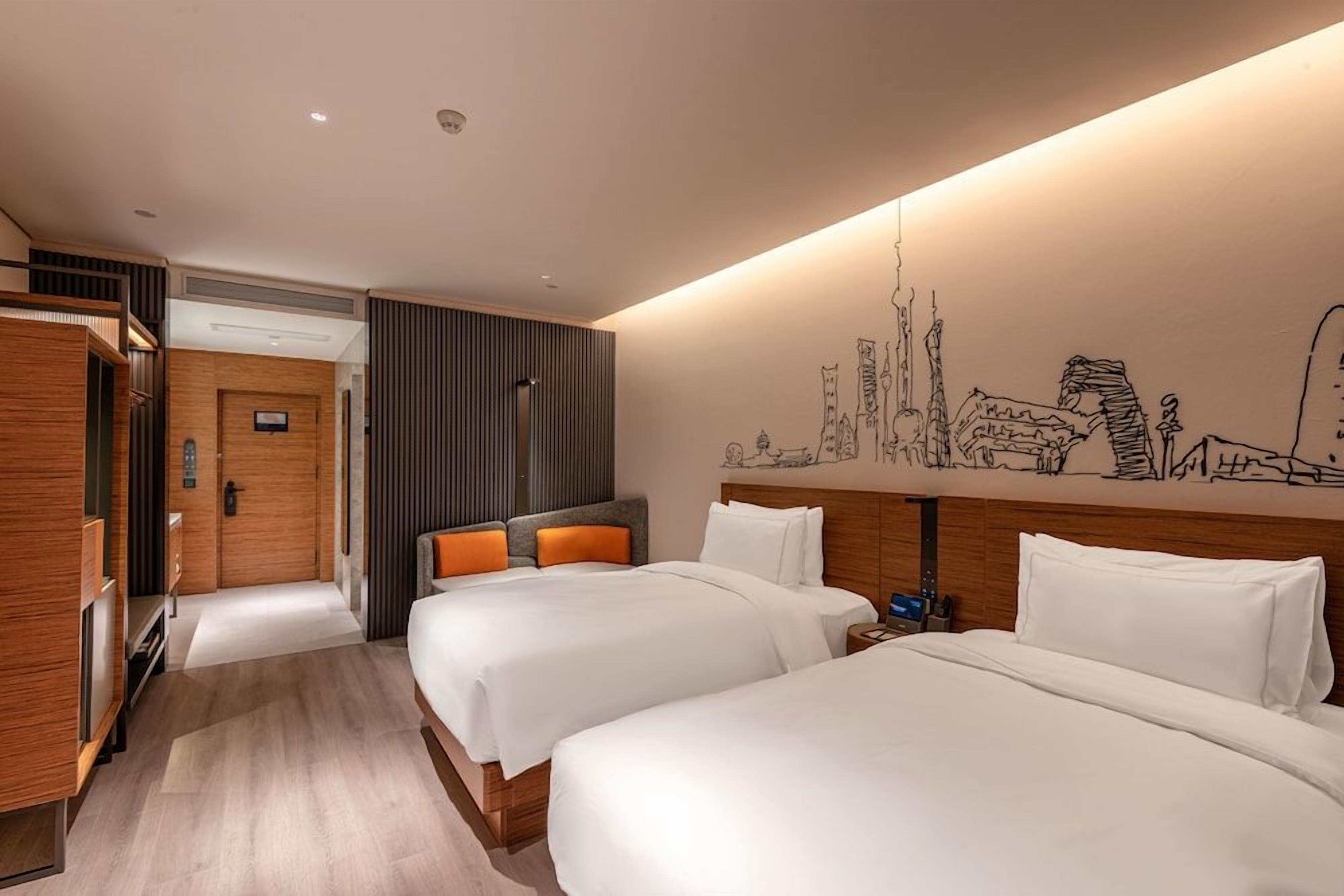 Una habitación de hotel con dos camas, un mural de paisaje urbano y un armario de madera.